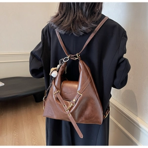 Détail du cabas en cuir marron foncé avec charm de baseball et logo embossé chic