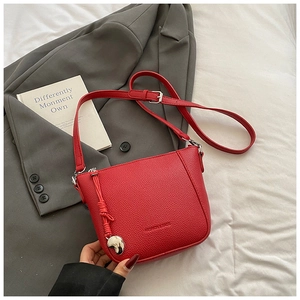 Detail of red litchi grain crossbody bag with silver heart pendant and fashion logo