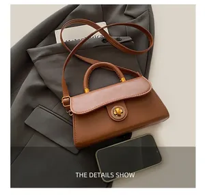 Braune Vintage Trapez-Tasche mit goldenem Drehverschluss neben einem Smartphone