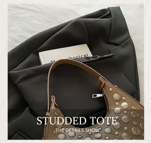 Close-up of retro dark camel studded hobo bag featuring silver rivets and crescent shape