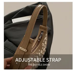 Detail of khaki bucket bag featuring silver rivets and an adjustable shoulder strap