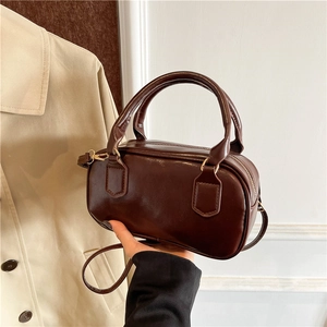 Sac à main bowling chic en cuir marron avec détails dorés et doubles poignées
