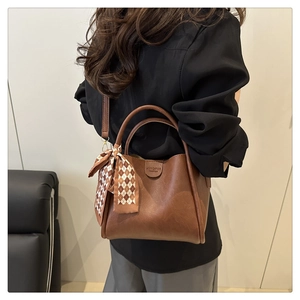 Dettaglio di una borsa a secchiello vintage in pelle marrone con sciarpa e tracolla