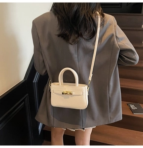 Detail of off-white crocodile pattern crossbody bag with gold rotating lock on model