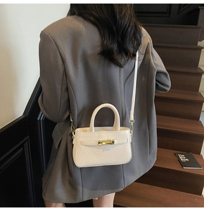 Detail of cream crocodile embossed handbag with gold lock and sleek shoulder strap