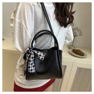 Dettaglio borsa a secchiello nera in similpelle con foulard a scacchi e finiture dorate