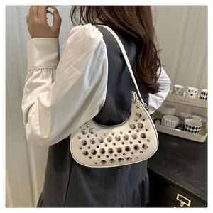 Model wearing white crescent underarm bag with silver rivets and sleek synthetic leather