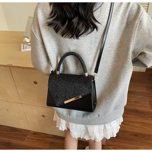 Detail of elegant black shoulder bag with sequined flap and gold metal trim on model