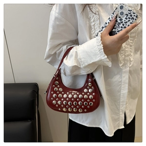 Detail of burgundy half-moon shoulder bag with silver studs and retro chic aesthetic