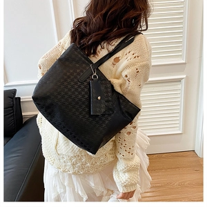 Detail of black houndstooth embossed tote bag with matching pendant shown on a model