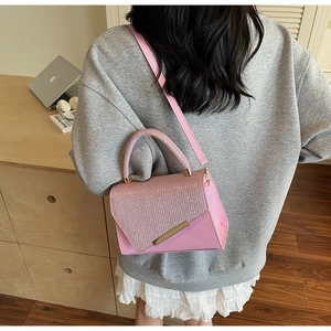 Detailed close-up of pink fashion handbag with sparkling sequins and gold metal bar accent