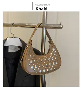 Detail of khaki crescent shoulder bag featuring silver rivets and metal display stand