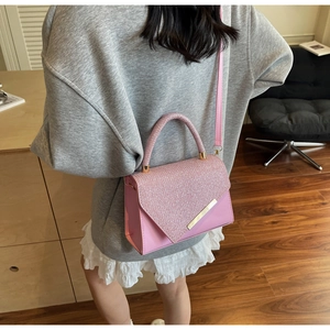 Rear view of model wearing a pink glitter handbag with metallic trim and crossbody strap