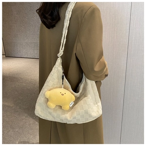 Close-up of beige quilted checkerboard hobo bag with yellow cloud plush charm detail