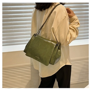 Detail of olive green faux leather tote bag with vintage chain strap and glossy finish