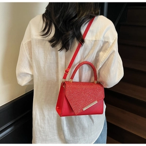 Detail of red rhinestone clutch bag featuring asymmetrical flap and silver metal trim
