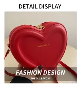 Close-up of red heart-shaped leather bag with dual gold zippers and gold fashion text