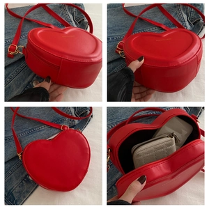 Detail view of red heart-shaped crossbody bag showing interior capacity and golden logo