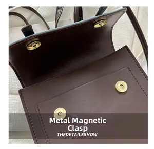 Nahaufnahme des goldenen Magnetverschlusses an einer braunen Lederhandtasche