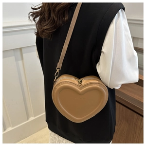 Detail of khaki heart-shaped crossbody bag with embossed text and gold-tone hardware