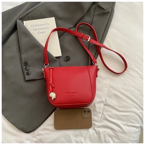 Detail of red lychee texture bucket bag with silver heart charm and branded embossing
