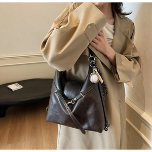 Détail du sac cabas en cuir marron foncé avec sangle croisée et charme baseball