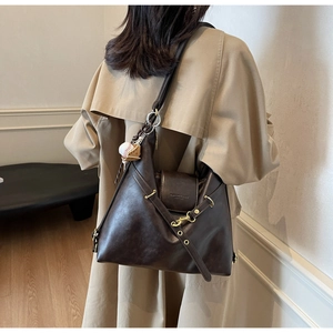 Détail du sac cabas en similicuir café avec boucles dorées et breloque sur manteau