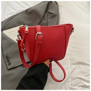 Close-up of red lychee textured bucket bag with adjustable strap and silver zipper detail