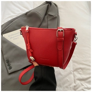 Detail of red pebbled leather crossbody bucket bag with silver hardware and adjustable strap