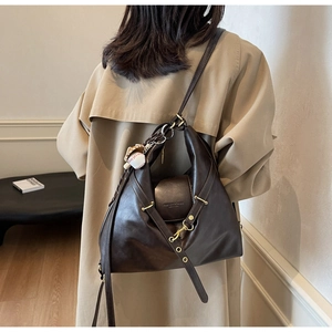 Détail du grand sac cabas en cuir marron foncé avec ferrures dorées porté par un mannequin
