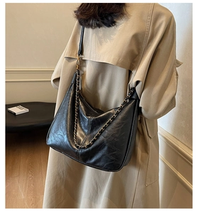 Close-up of black pleated leather tote bag featuring elegant gold chain strap details