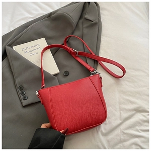 Detailed macro view of the red lychee texture leather on a stylish bucket crossbody bag