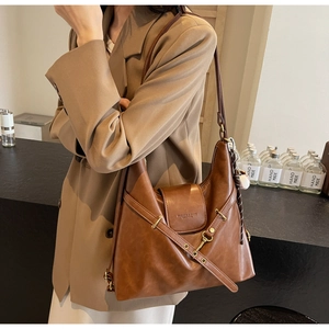 Détail du sac Hobo marron avec lanières croisées et boucle dorée sur un blazer élégant