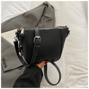 Close-up of black lychee grain leather bucket bag with silver zipper and adjustable strap
