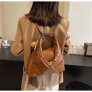 Sac hobo vintage en cuir marron porté en sac à dos dans un café chaleureux