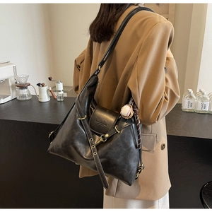 Détail d'un grand sac cabas noir en cuir avec fermoir à rabat et pendentif baseball