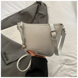 Close-up of silver crossbody bucket bag with litchi texture and adjustable shoulder strap