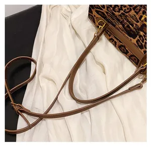 Detail of the brown leather shoulder strap and gold hardware on the leopard print tote bag