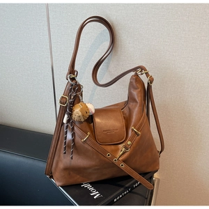 Détail d'un sac cabas marron vintage avec logo embossé et breloque de baseball chic