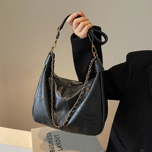 Chic black hobo bag in soft pebbled leather with chain and wide strap, lifestyle shot