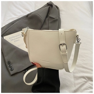 Detail of white lychee leather bucket bag with silver buckle and embossed fashion text