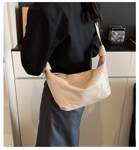 Detail of soft cream leather hobo bag showing side stitching and seamless wide shoulder strap