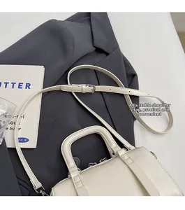 Detail of cream Boston bag with adjustable strap and top handle on dark suit