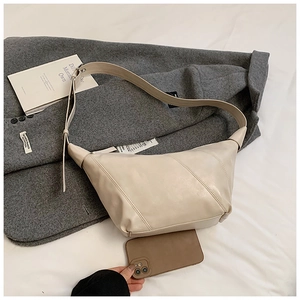 Detailed size comparison of the beige crescent shoulder bag next to a smartphone