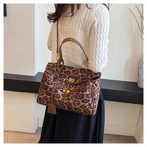 Detailed shot of leopard print tote featuring brown leather handles and gold twist locks