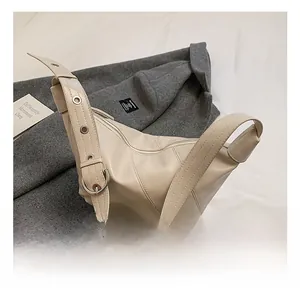 Detail of beige leather hobo bag featuring silver eyelets and a large buckle on shoulder strap