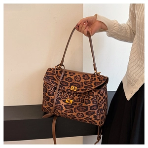 Detail of leopard print tote bag with golden twist-lock closures and textured leather finish