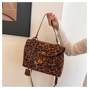 Detail of leopard print tote bag featuring a gold twist lock and brown leather handle