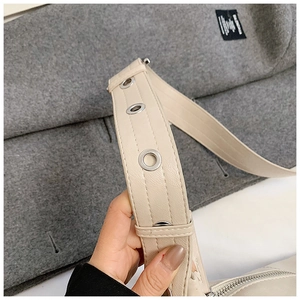 Detail of cream leather shoulder bag with silver metal eyelets and textured litchi grain