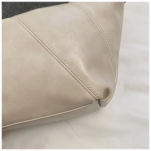 Detail view of beige leather dumpling bag showing fine texture and double stitching